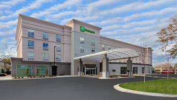 Un hotel Holiday Inn con un diseño moderno, que presenta una entrada cubierta y varios pisos.