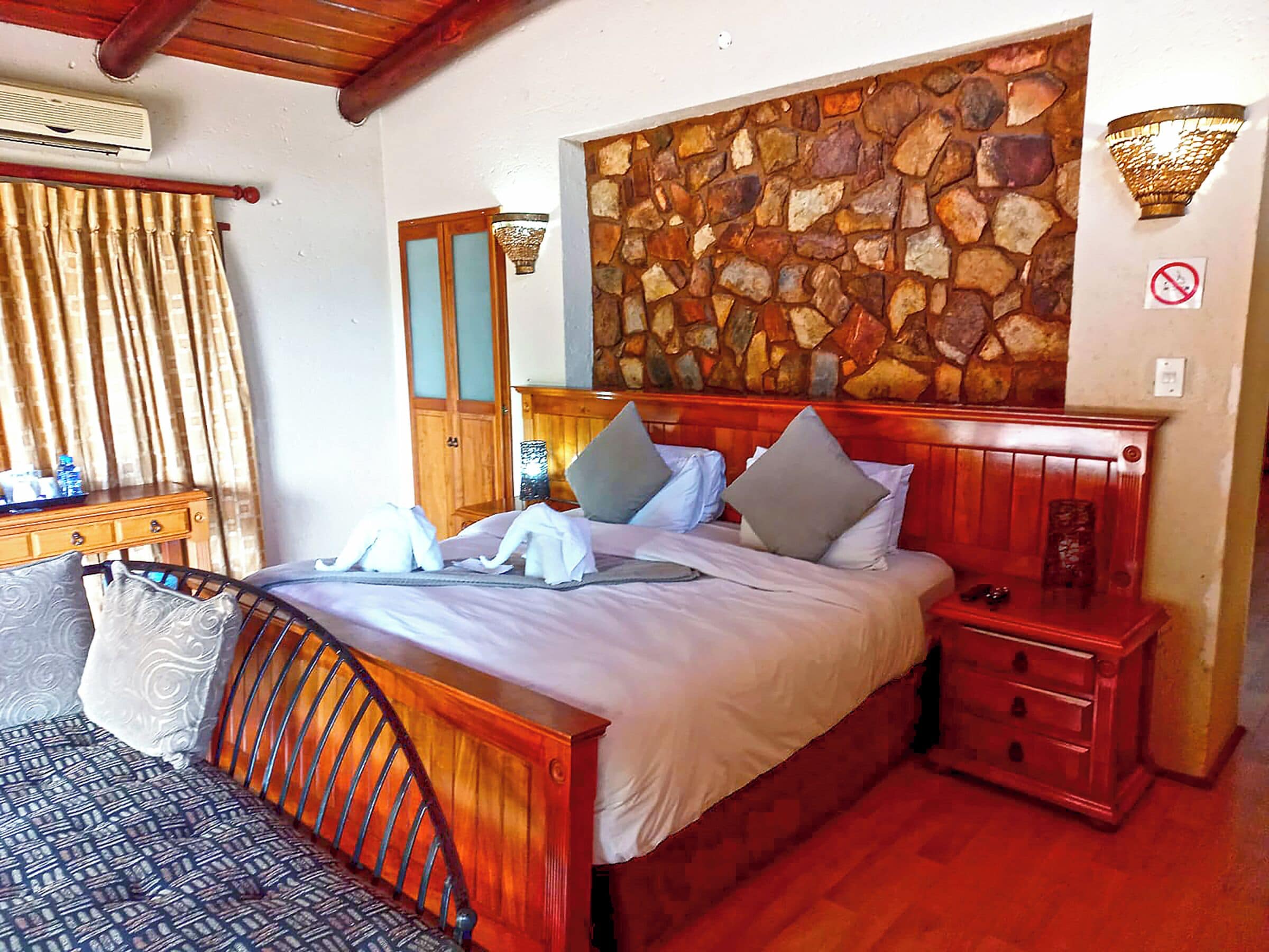 A bedroom with a stone wall, wooden bed frame, and a nightstand.