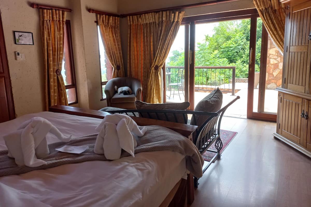 Ein Hotelzimmer mit Bett, Sessel, Tisch und Blick ins Freie.