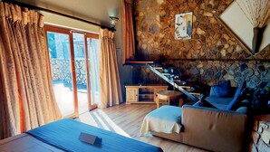 Um quarto com cama, sofá, mesinha e parede de pedra.