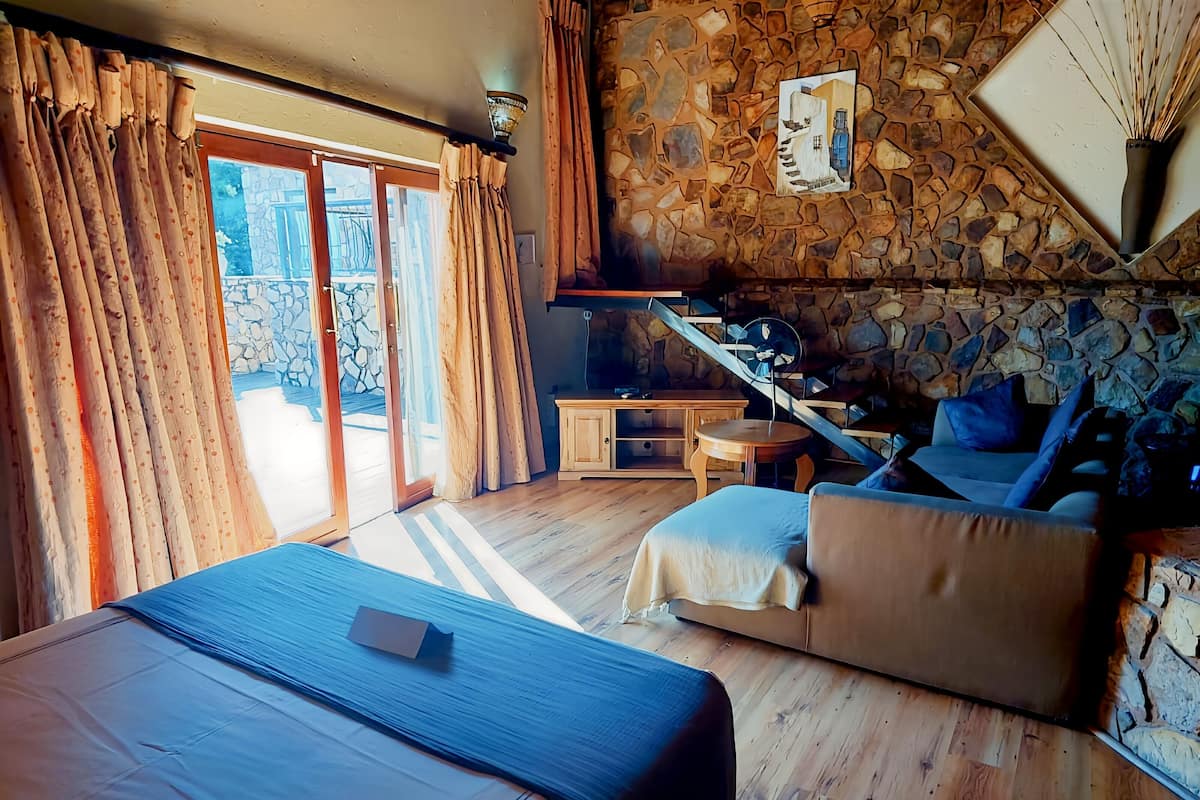 Ein Zimmer mit einem Bett, einem Schlafsofa, einem kleinen Tisch und einer Steinwand.