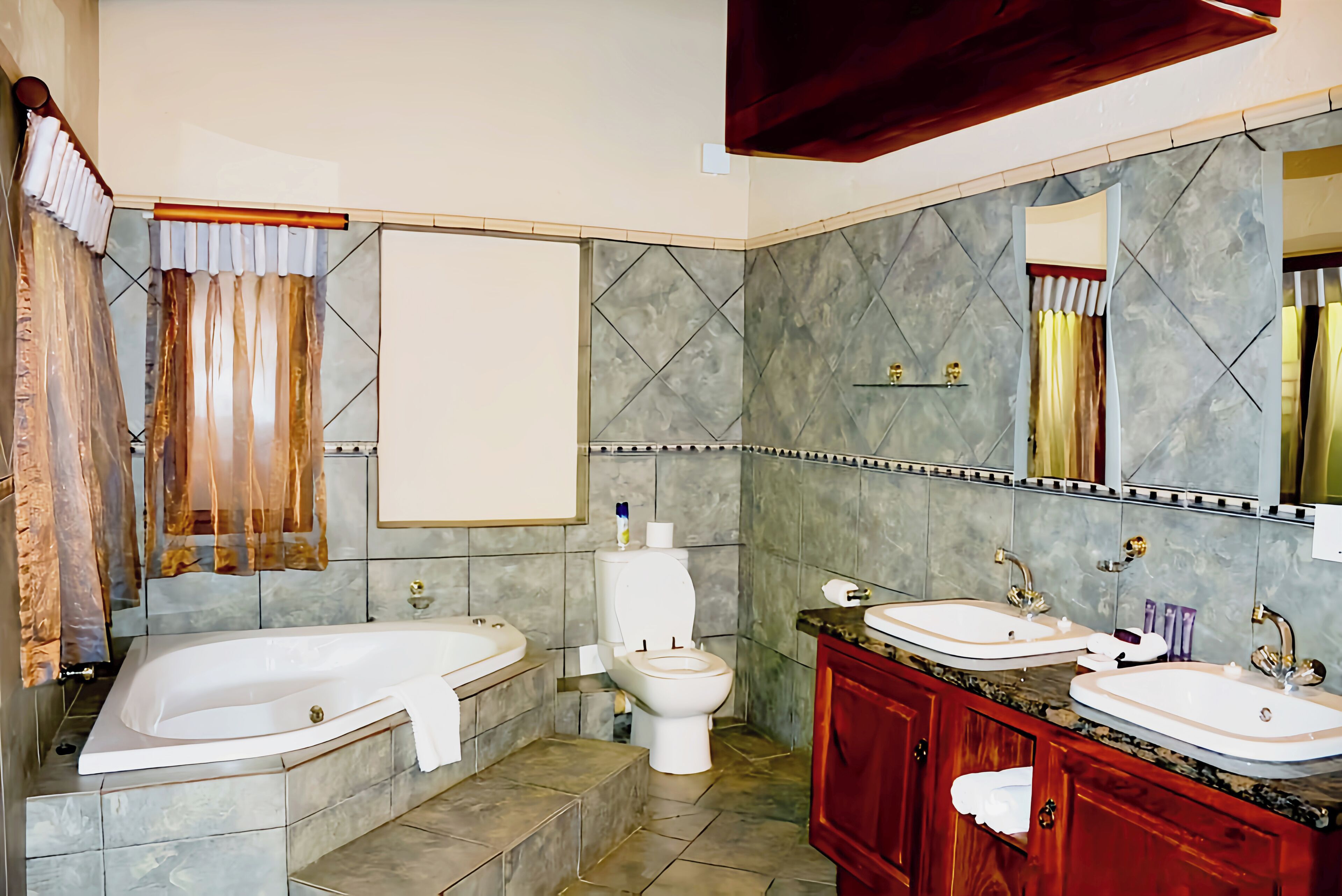 A bathroom with a bathtub, toilet, and double sink vanity.