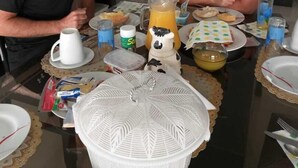 Een eettafel met borden, bekers en een karaf in een moderne keuken met witte kasten en een betegelde achterwand.