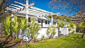 A white house with a sloped roof, surrounded by green grass and small palm trees. - 3 & 4 Bedroom Houses in Seaview Crescent (Picton)
