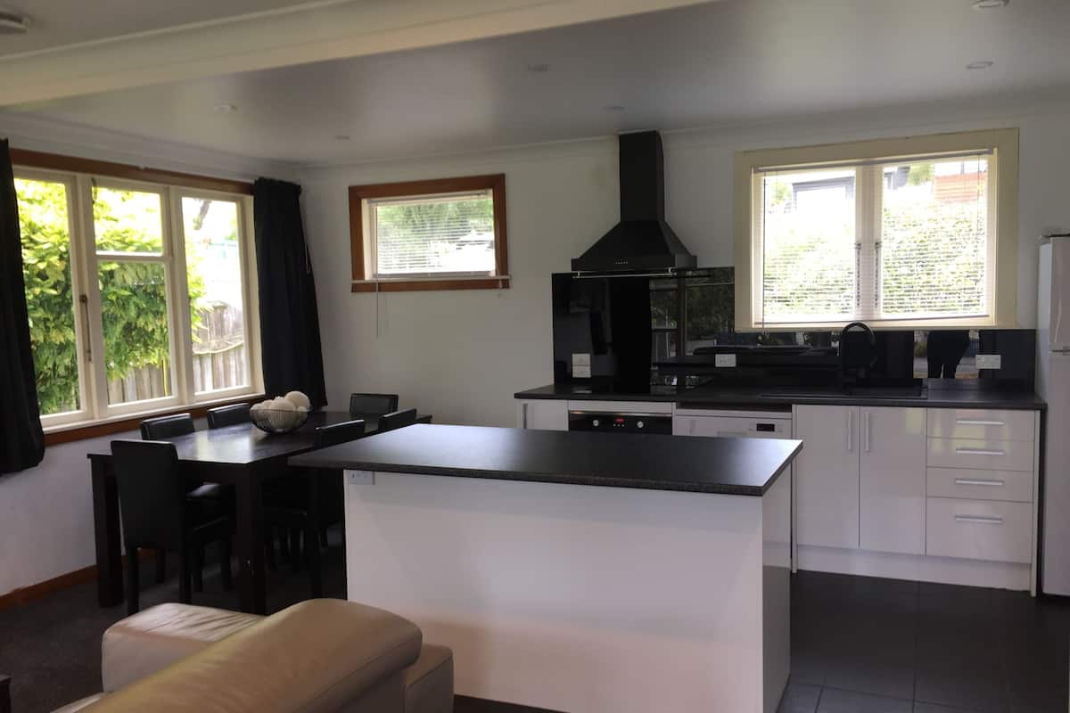 A modern kitchen with a central island, a dining area with chairs, and a sofa.