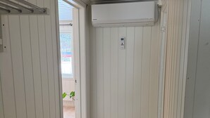 Un passadís amb revestiment de fusta, unitat de condicionador d'aire penjada al sostre i una porta que dona a una zona exterior.