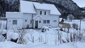 Una casa blanca de dues plantes amb un teulat cobert de neu i un porxo davanter.