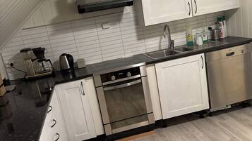 A modern kitchen with white cabinets, a black countertop, and a stainless steel oven.