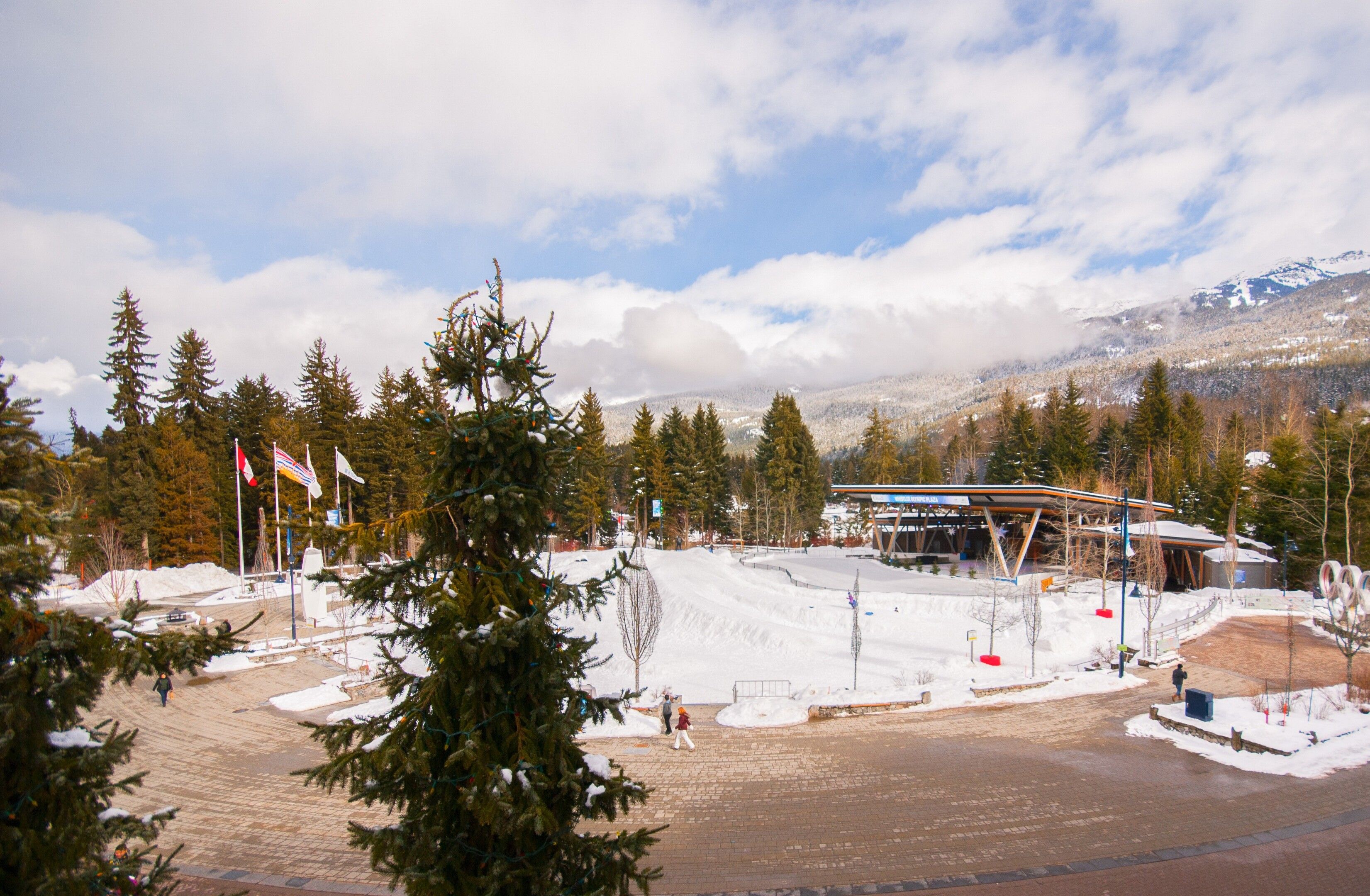 A ski resort with a covered area, snow-covered ground, and a mountain in the background.