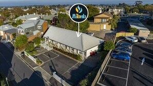 A building with a parking lot, a sign with a flame logo, and a view of the surrounding neighborhood.