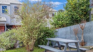 A picnic table in a garden with a house in the background.