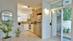 A modern kitchen with stainless steel appliances, wooden cabinets, and a large window. - Our flat is a great base to explore everything that South Australia offers... (West Beach)