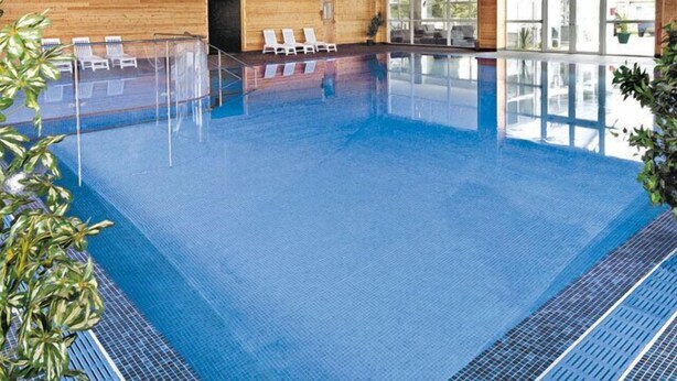 An indoor swimming pool with clear blue water, wooden walls, and a glass door leading outside. - FANTASTIC LODGE - FREE FACILITIES And WiFi  (Newquay)
