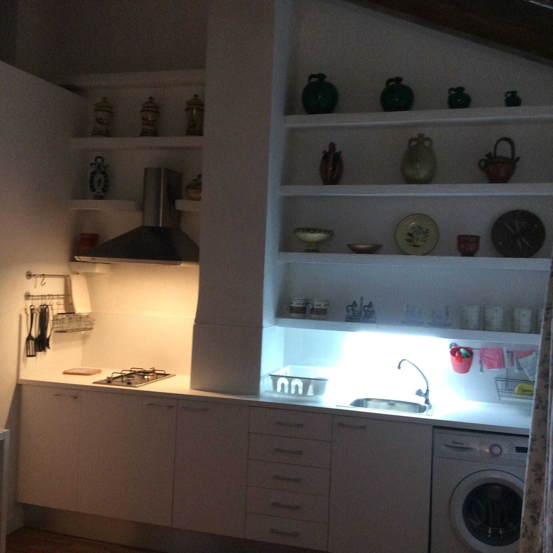 A compact kitchen with a built-in stove, a sink, and a washing machine.
