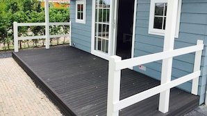 A blue house with a wooden deck and white railings.