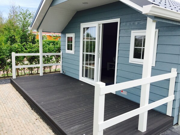 A blue house with a wooden deck and white railings.