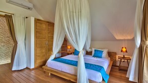 A bedroom with a canopy bed, wooden wardrobe, and two bedside lamps.