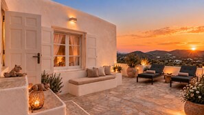 A sunset view from a rooftop terrace with a sofa, lounge chairs, and potted plants. - SEA & SUN A Quality Brand Certified Villa 150 meters from Agia Anna Beach (MYKONOS)