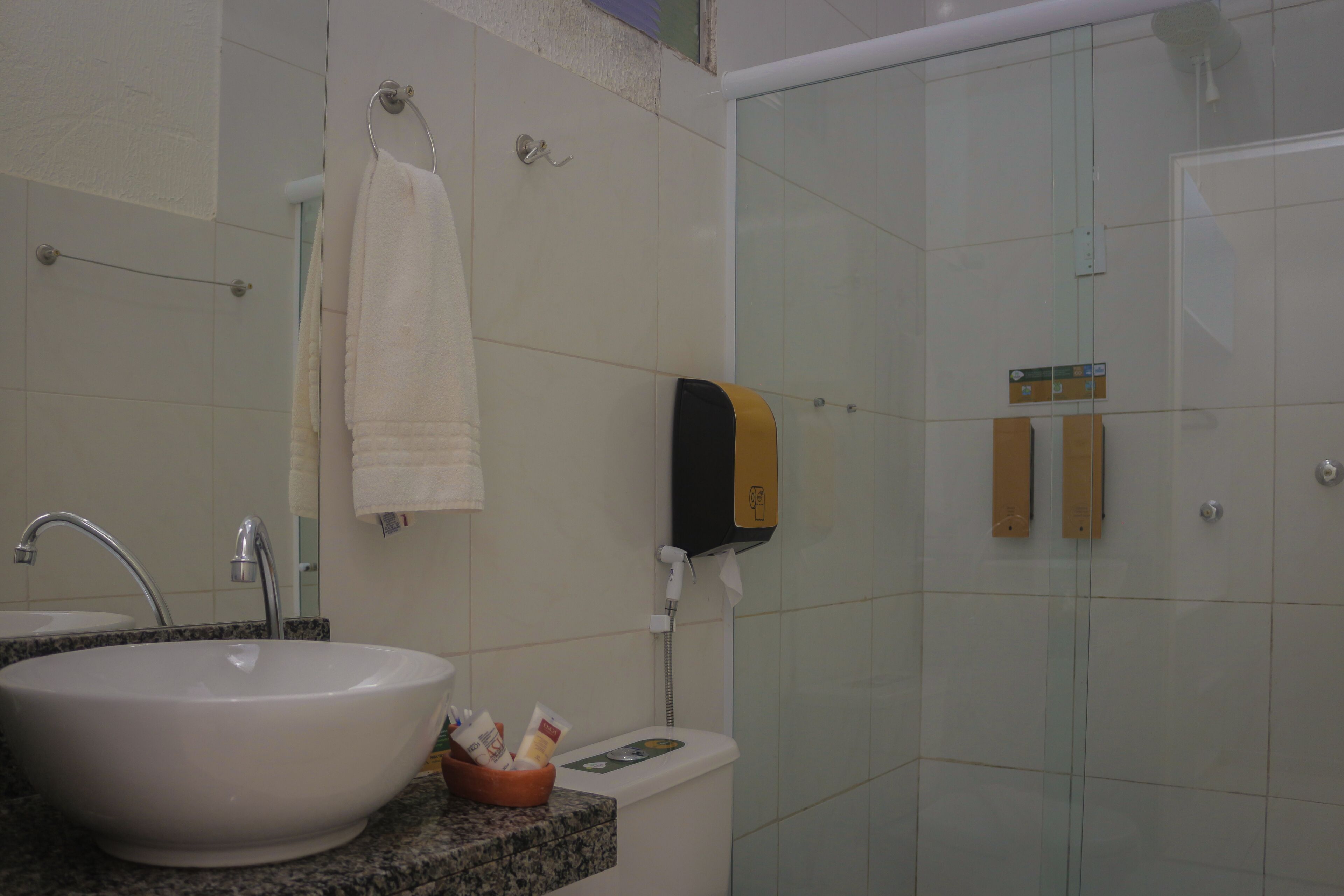 Bagno con lavandino, specchio, porta asciugamani e cabina doccia in vetro.