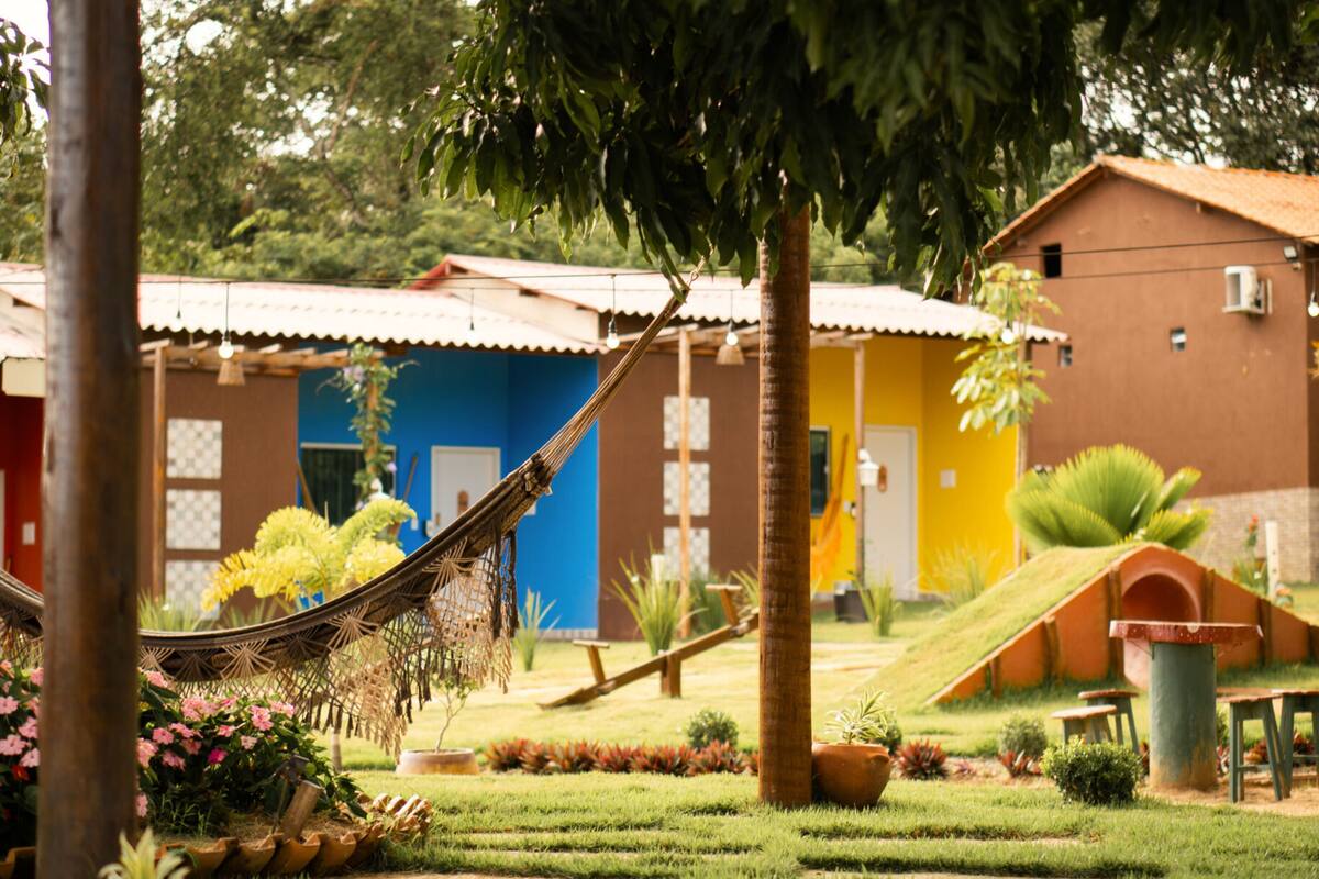 A garden with a hammock, potted plants, and a building with a tiled roof.