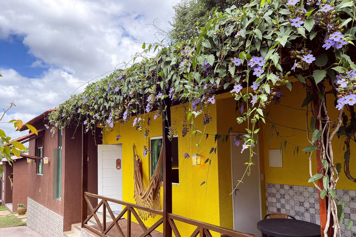 A yellow building with a balcony, a door marked '12', and a table with chairs outside.