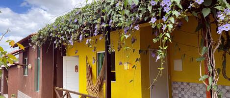 Un bâtiment jaune avec un balcon, une porte portant le numéro « 12 », et une table avec des chaises à l’extérieur.