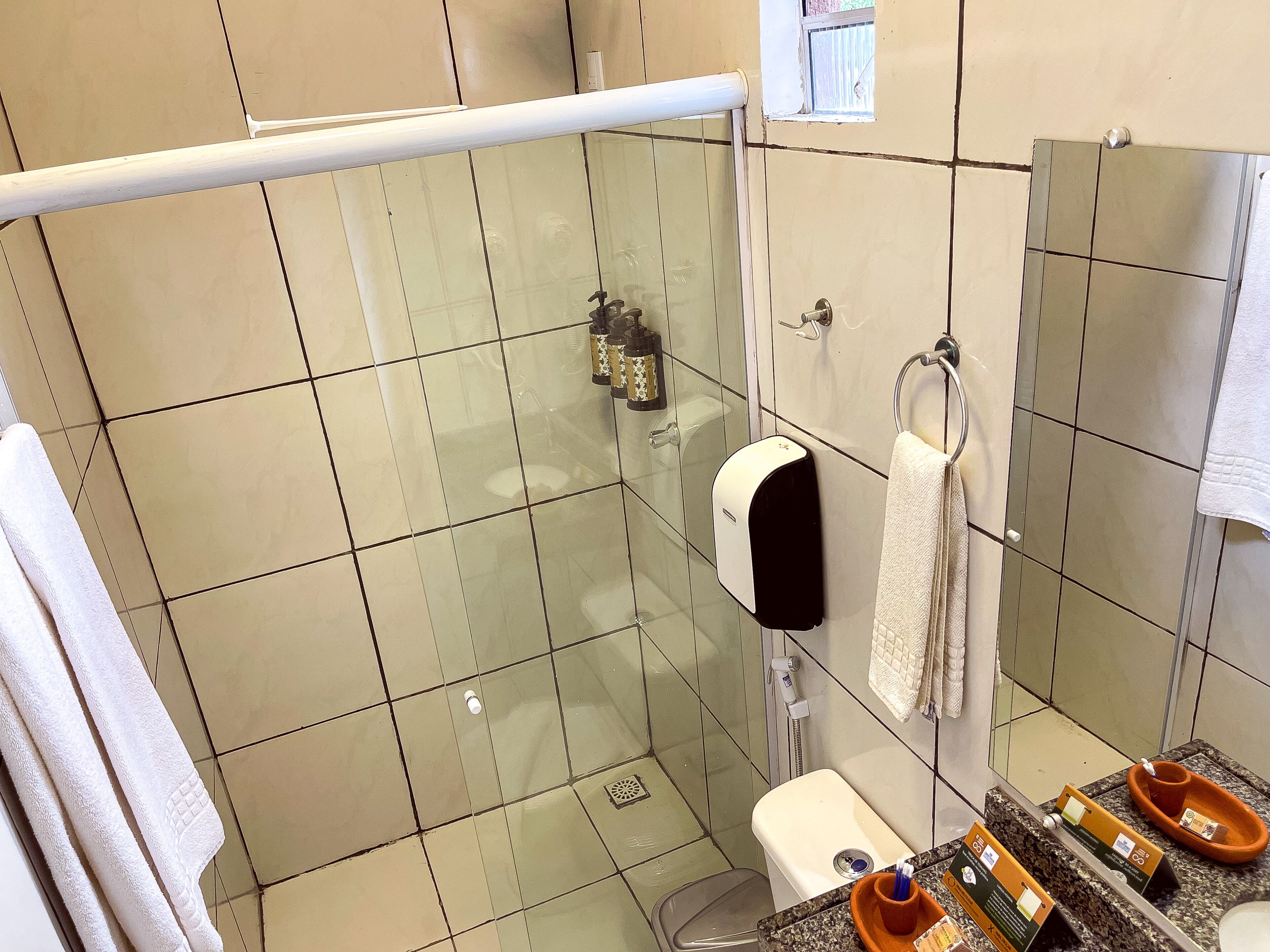 Ein Badezimmer mit Duschkabine aus Glas, Toilette, Waschbecken und Handtuchhalter.
