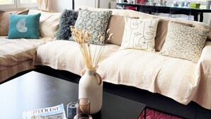 A living room with a sofa, a coffee table, a magazine, and a vase with dried plants. - APARTMENT LA COLLINE 4 EPIS - Villas des Sables (Fréhel)