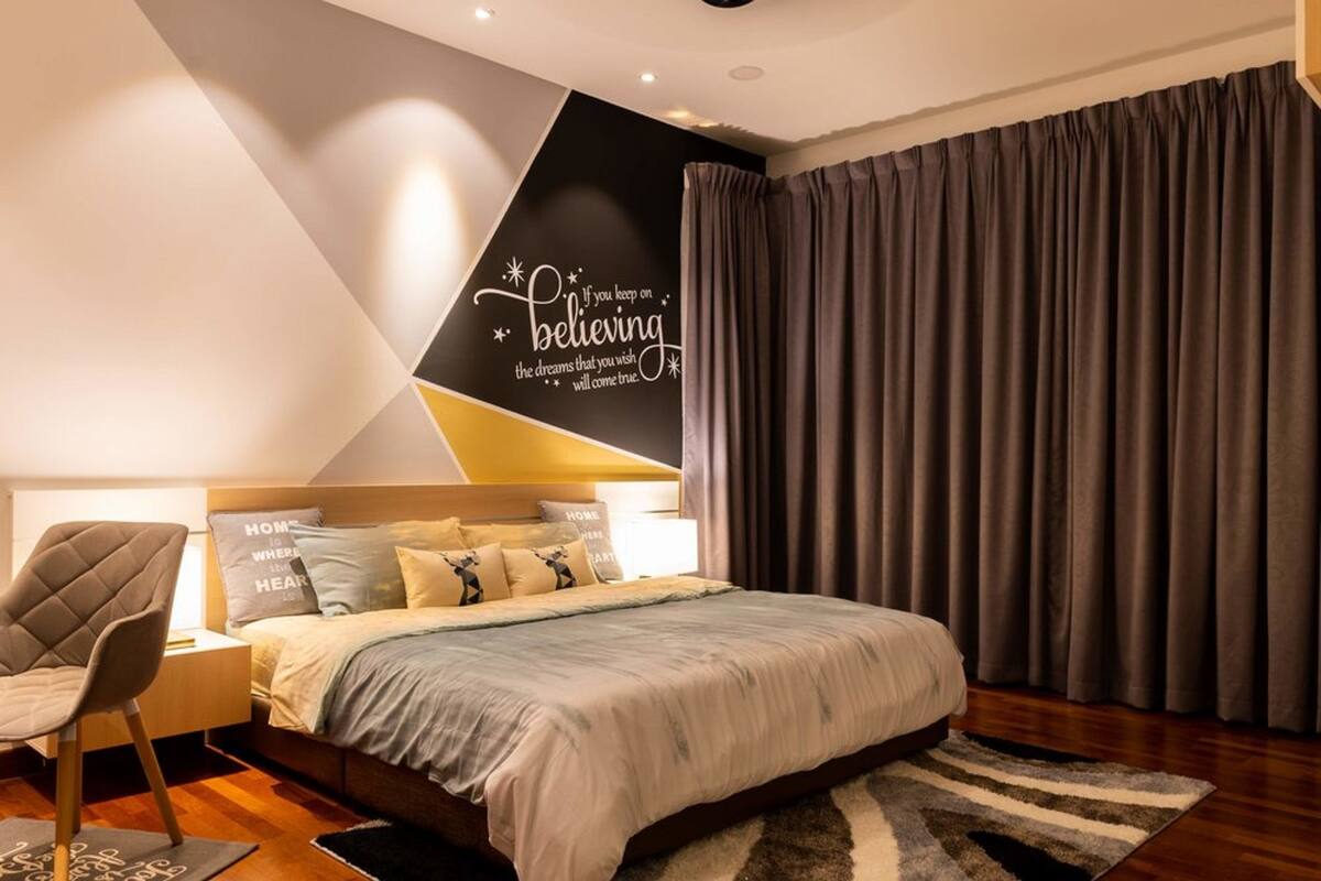 A modern bedroom with a bed, a nightstand, a chair, and a wall with motivational text.