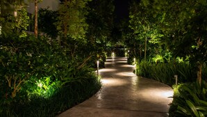 A well-lit pathway surrounded by lush greenery, leading to a building entrance. - Southwest Designer's Suite by D Imperio Homestay (George Town)