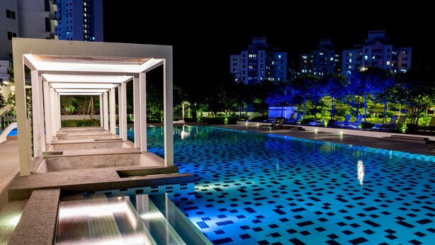A swimming pool with a geometric tile pattern, a covered walkway, and modern buildings in the background. - Southwest Designer's Suite by D Imperio Homestay (George Town)