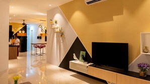 A modern living room with a flat-screen TV, a white console table, and a mounted air conditioner. - Southwest Designer's Suite by D Imperio Homestay (George Town)