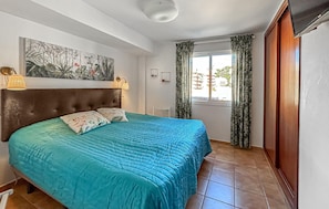 Quarto com cama, janela com cortinas, um quadro na parede e uma luminária no teto.