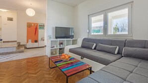 Una sala de estar moderna con un sofá gris, un televisor de pantalla plana y una mesa de centro a rayas de colores.