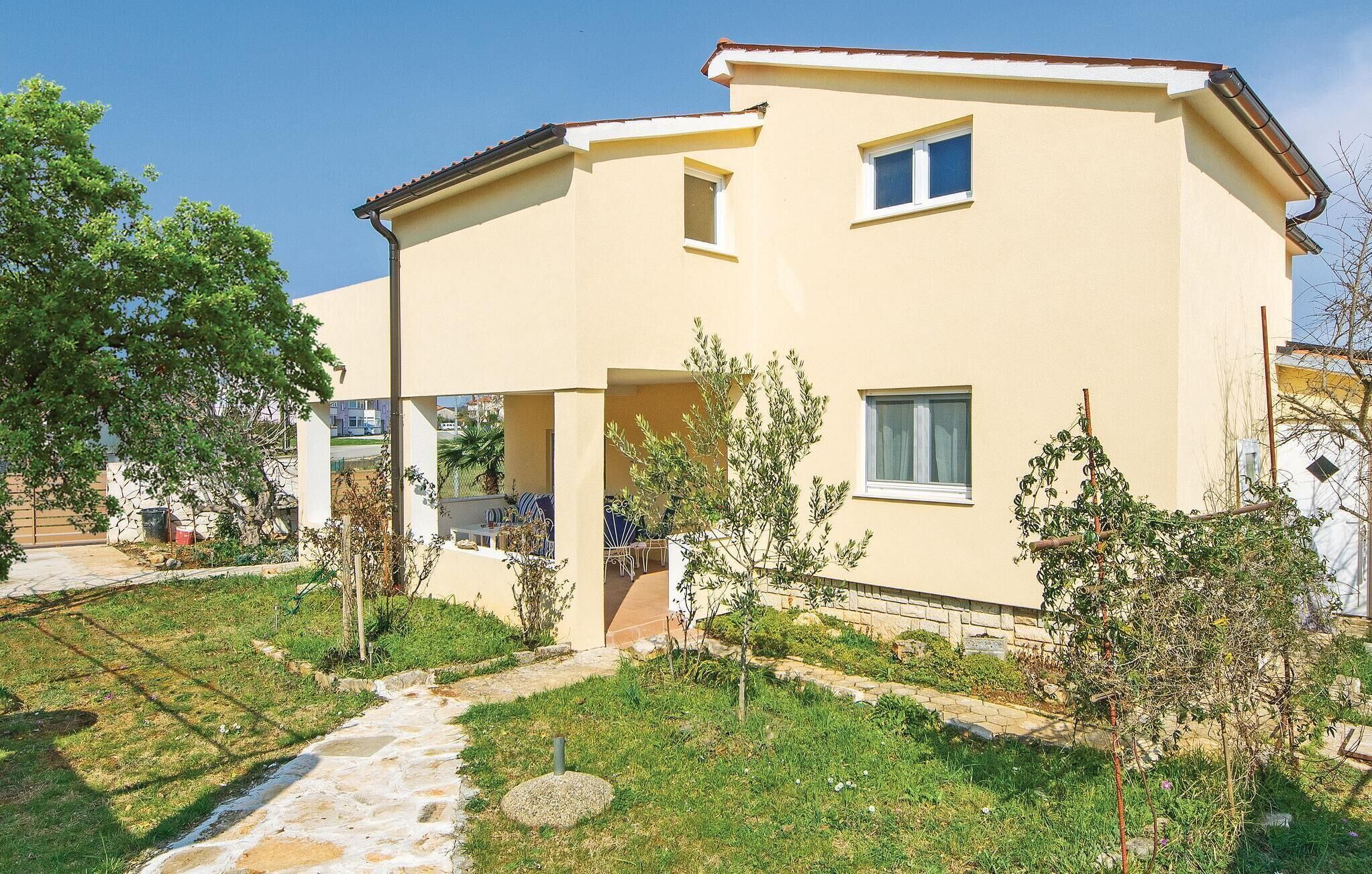 A two-story house with a flat roof, a small balcony, and a garden with a stone pathway.