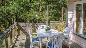 Eine Holzterrasse mit Tisch und Stühlen, umgeben von Bäumen.