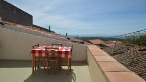 A table set with a red and white checkered tablecloth, wooden chairs, and a view of a distant landscape with buildings and a clear sky. - Modern renovated holiday home with panoramic terrace, close to sea and mountains (Seneghe)