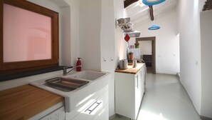 A modern kitchen with a built-in sink, wooden countertop, and a window with a pink view. - Modern renovated holiday home with panoramic terrace, close to sea and mountains (Seneghe)