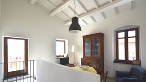A room with a dining table, a blue sofa, a wooden cabinet, and a hanging lamp. - Modern renovated holiday home with panoramic terrace, close to sea and mountains (Seneghe)