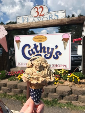 Ein Eis in einem Waffelhorn vor einem Schild des Eisgeschäfts Cathy’s Ice Cream Shoppe.
