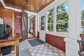 A kitchen with a refrigerator, a wooden table, and a window with a view of trees.