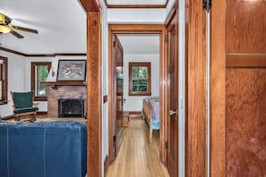 A hallway with a fireplace, a bed, and a chair.