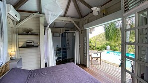Une chambre à coucher avec un lit, une table de chevet, une fenêtre et une vue sur une piscine.