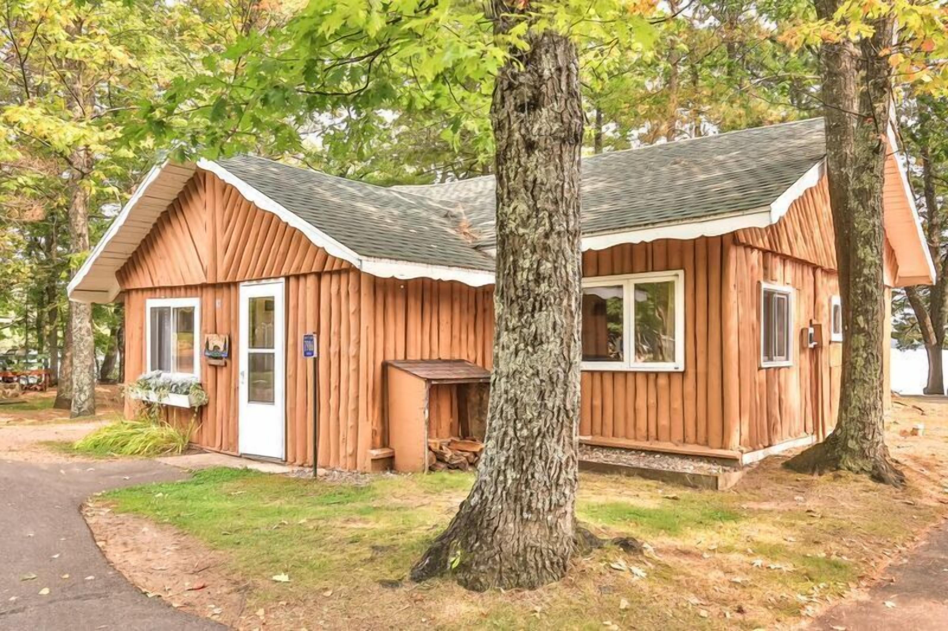 A wooden cabin with a gabled roof, a front door, and a small porch area.