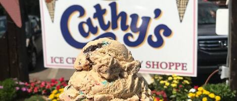 An ice cream cone in front of a shop sign for Cathy’s Ice Cream Shoppe.