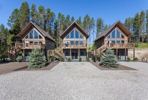 A symmetrical lodge with two main buildings connected by a central entrance. Each building features a balcony with wooden railings and a covered porch. - Going to the Sun Chalet A/Canadian Chalet (West Glacier)