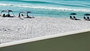 Une plage avec des parasols et des chaises longues, une vue dégagée sur l’océan et une rive sablonneuse.