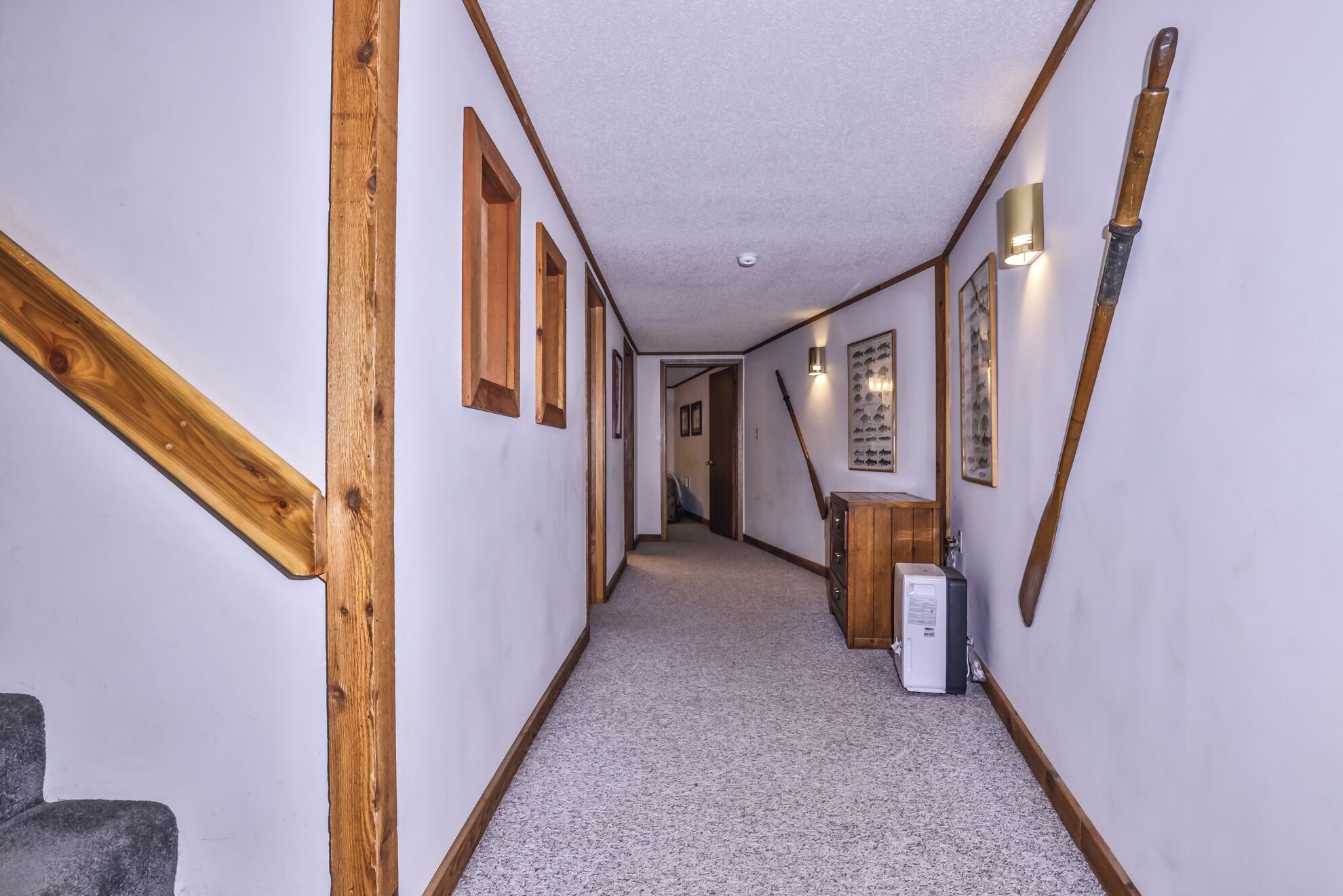 A narrow hallway with wooden beams, a carpeted floor, and framed pictures on the walls.