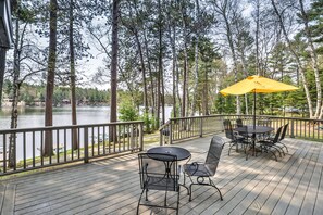 Una terraza con mobiliario exterior y un paraguas amarillo con vista a un lago.