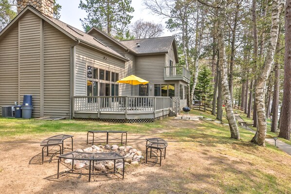 A two-story house with a covered porch, outdoor seating, and a fire pit.